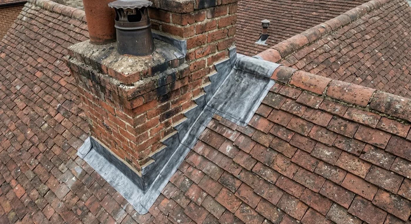 A lead flashing detail on a roof abutment photographed close, showing the join between two materials